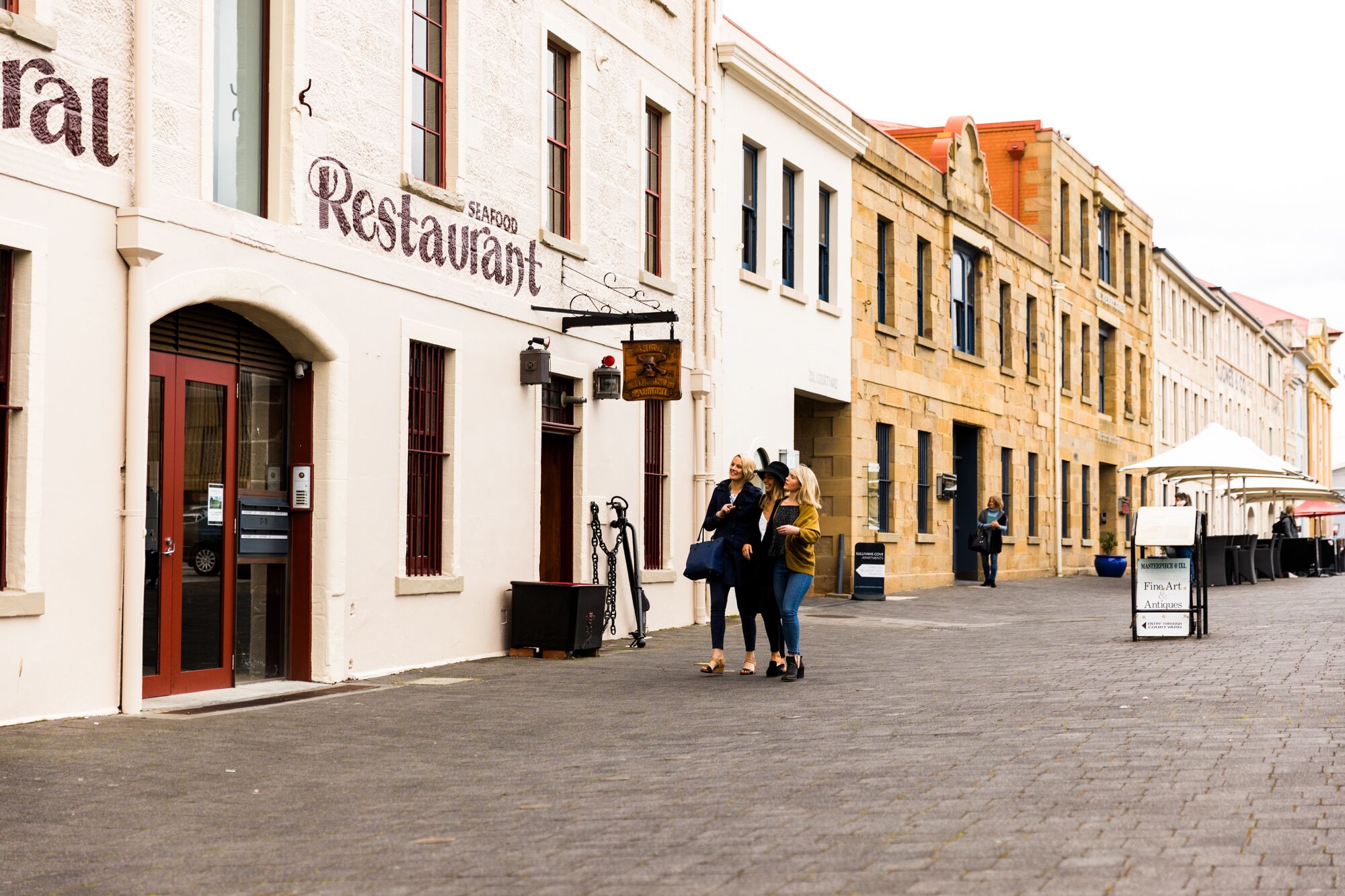 A street with a restaurant named "Restaurant Seafood" and a sign for "Masterpiece Fine Art Antiques".