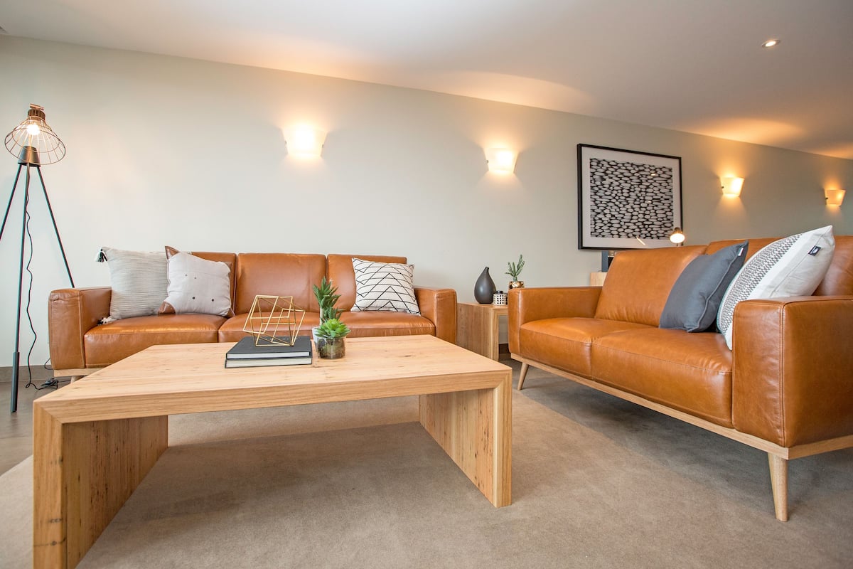 A modern living room with two leather sofas, a wooden coffee table, and a floor lamp.