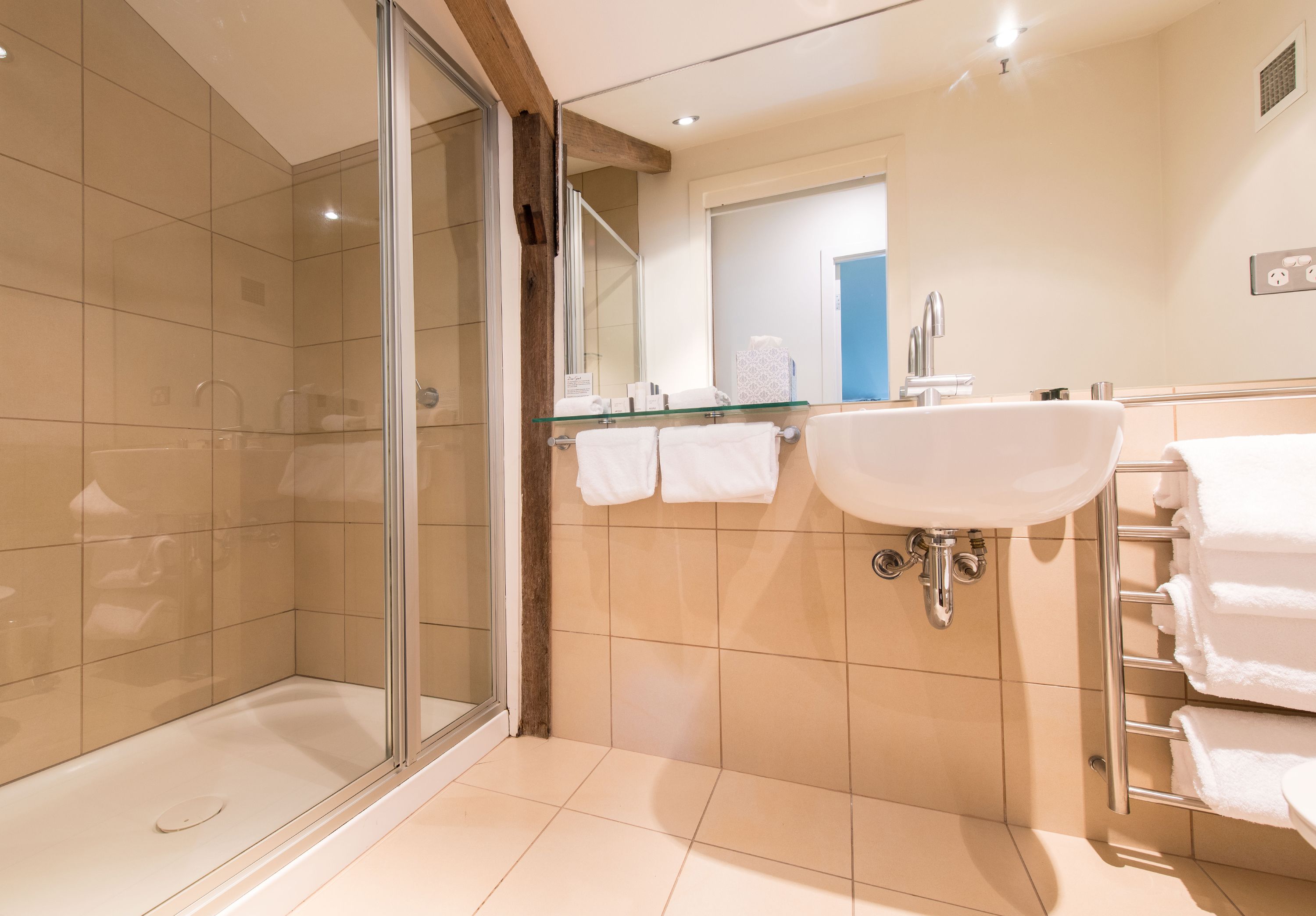 Un baño moderno con ducha de vidrio, lavamanos con superficie de vidrio y un perchero para toallas.