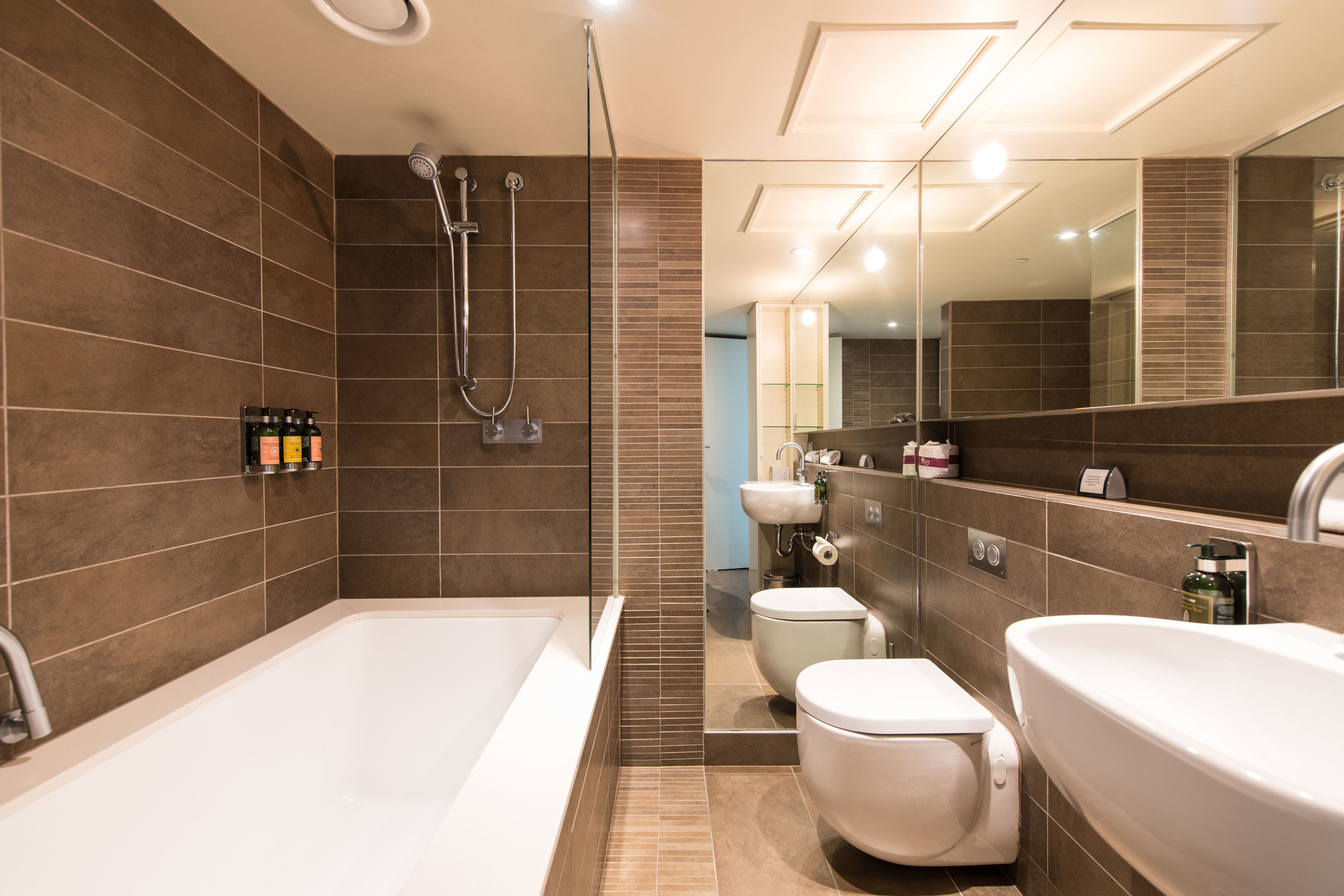 Een moderne badkamer met een bad, toilet en douche.