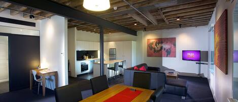 A modern office space with a long table, meeting chairs, a sofa, and a television.