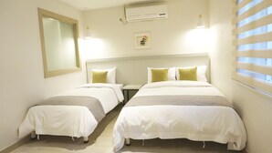 A hotel room with two single beds, a large mirror, an air conditioning unit, and a window with blinds. - Hotel Victoria (Seoul)