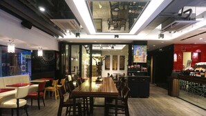 A modern restaurant with a long wooden table and chairs, a bar area, and a view of the city through large windows. - Hotel Victoria (Seoul)