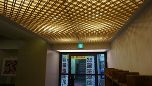 A restaurant interior with a grid-patterned ceiling, wooden benches, and a menu display at the entrance. - Hotel Victoria (Seoul)