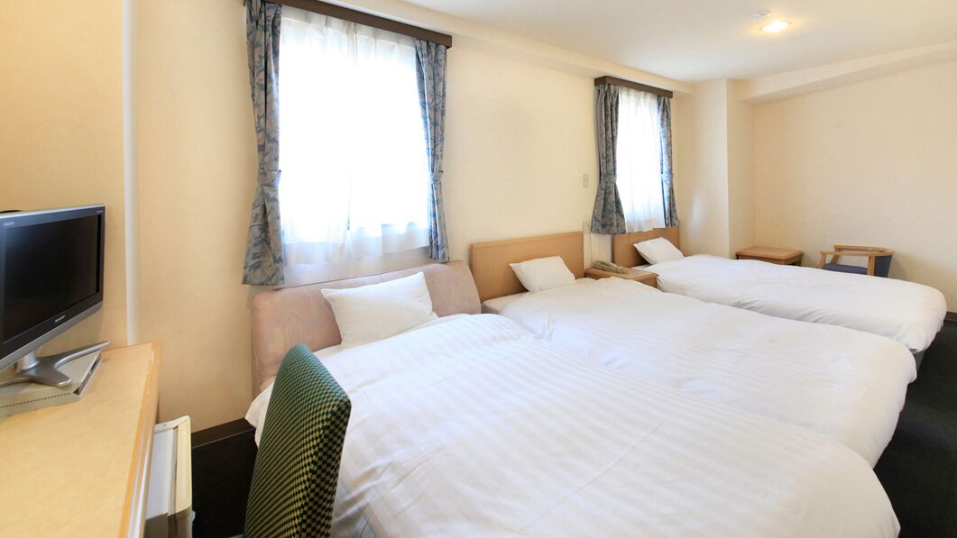 Una habitación de hotel con dos camas, un escritorio con computadora y televisión.
