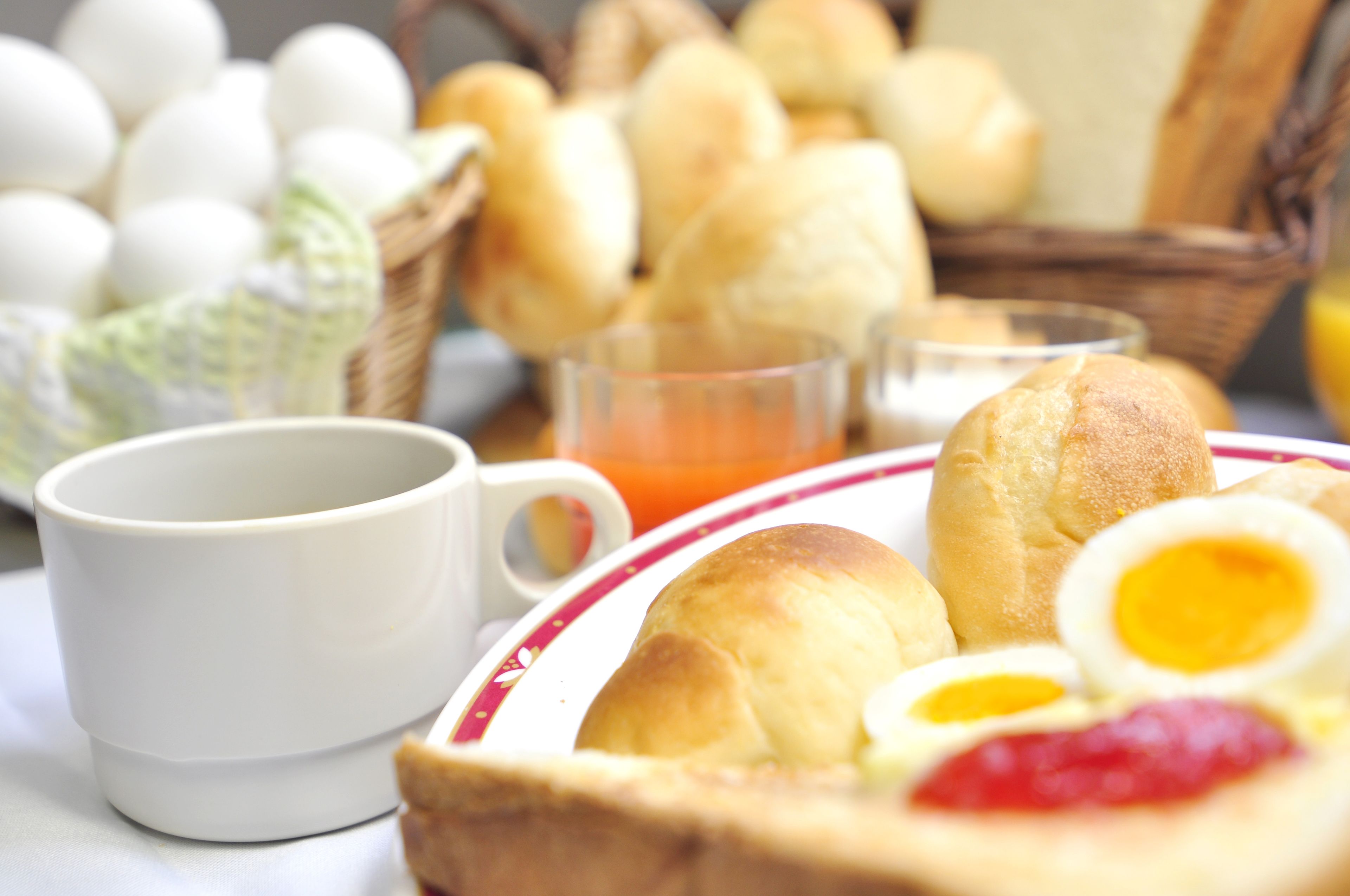 Ein Frühstückstisch mit Brötchen, Eiern und einer Tasse.