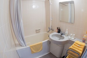 A bathroom with a bathtub, sink, mirror, and towel rack. - Marine House SEASIR Akajima (Zamami)