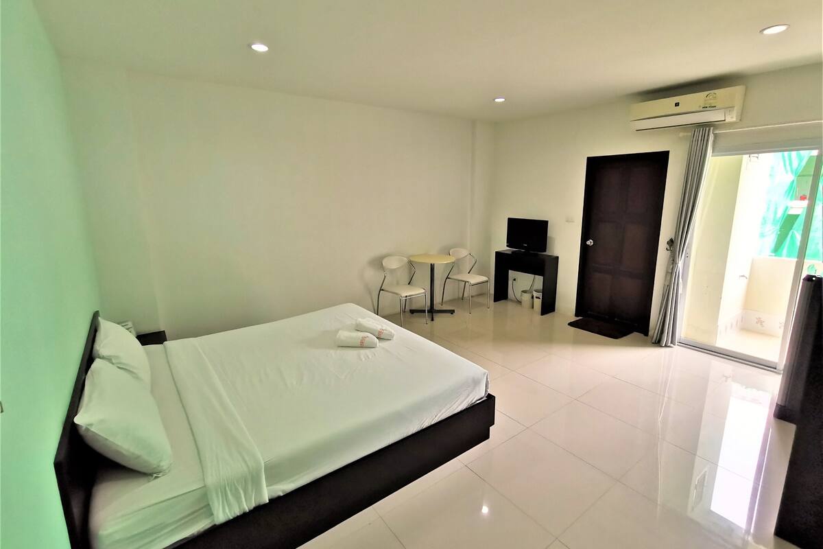 A hotel room with a bed, a desk, a chair, and a television.