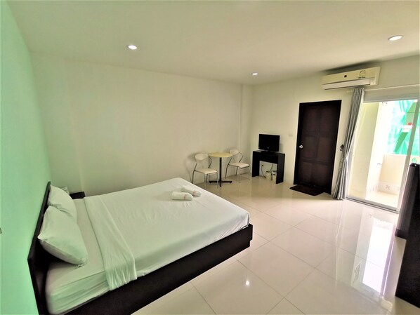 Una habitación de hotel con cama, escritorio, silla y televisor.