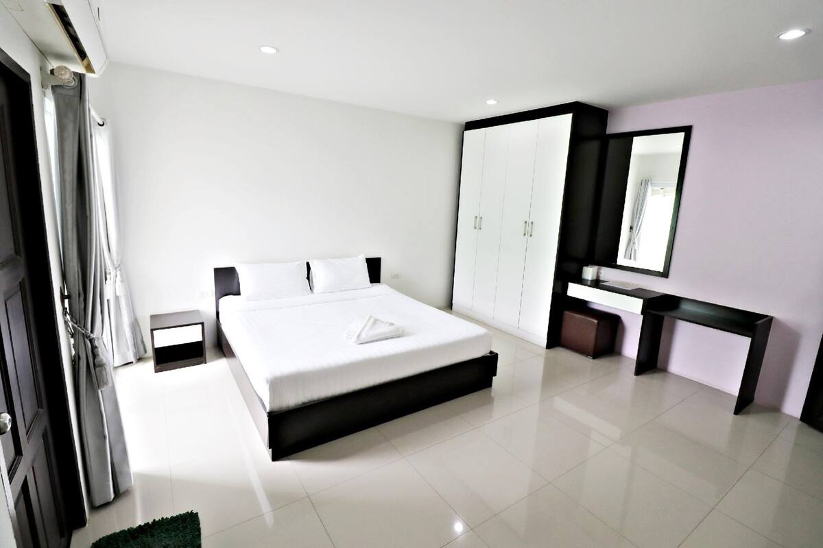 A modern bedroom with a large bed, a vanity with a mirror, and a wardrobe.