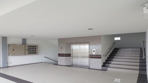 A spacious lobby with a tiled floor, a staircase, and a wall-mounted elevator. - Hua Hin Irooms Hotel (Hua Hin)