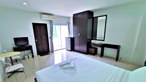 A hotel room with a large bed, a desk with a chair, a television, a wardrobe, and a mirror. - Hua Hin Irooms Hotel (Hua Hin)