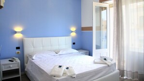 A hotel room with a large bed, bedside tables, a mirror, and a window with curtains. - Hotel Città Bella (Gallipoli)