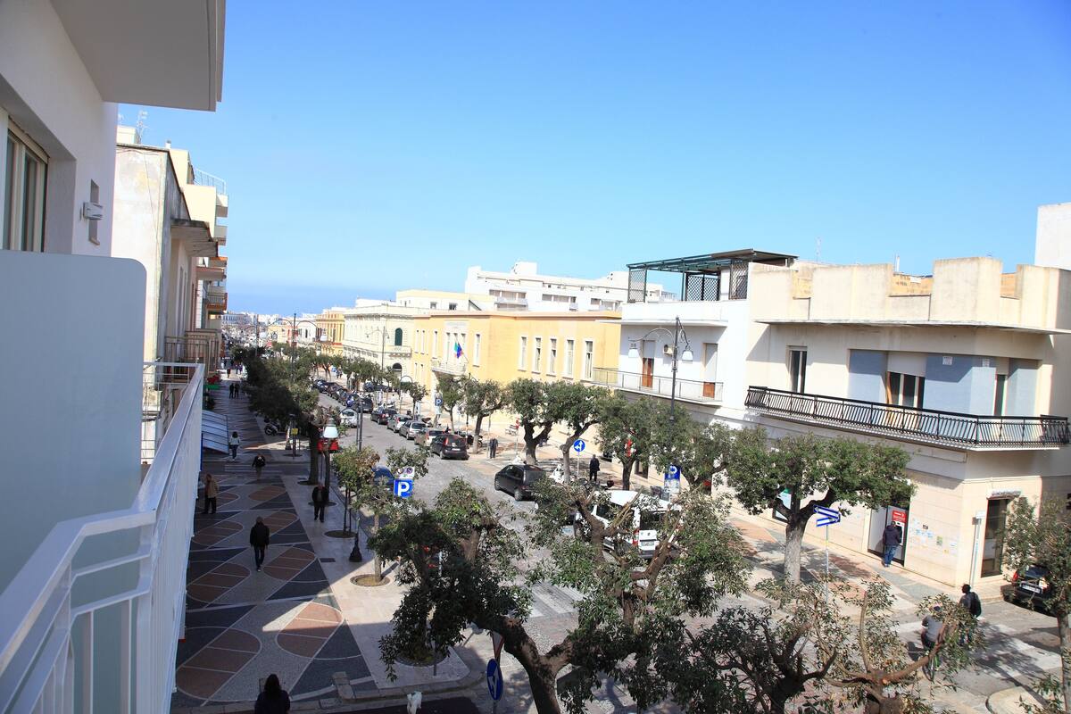 Vista de la calle con edificios, árboles y cielo despejado.