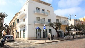 A white building with a ground-floor shop, a parking sign, and a pedestrian crossing. - Hotel Città Bella (Gallipoli)