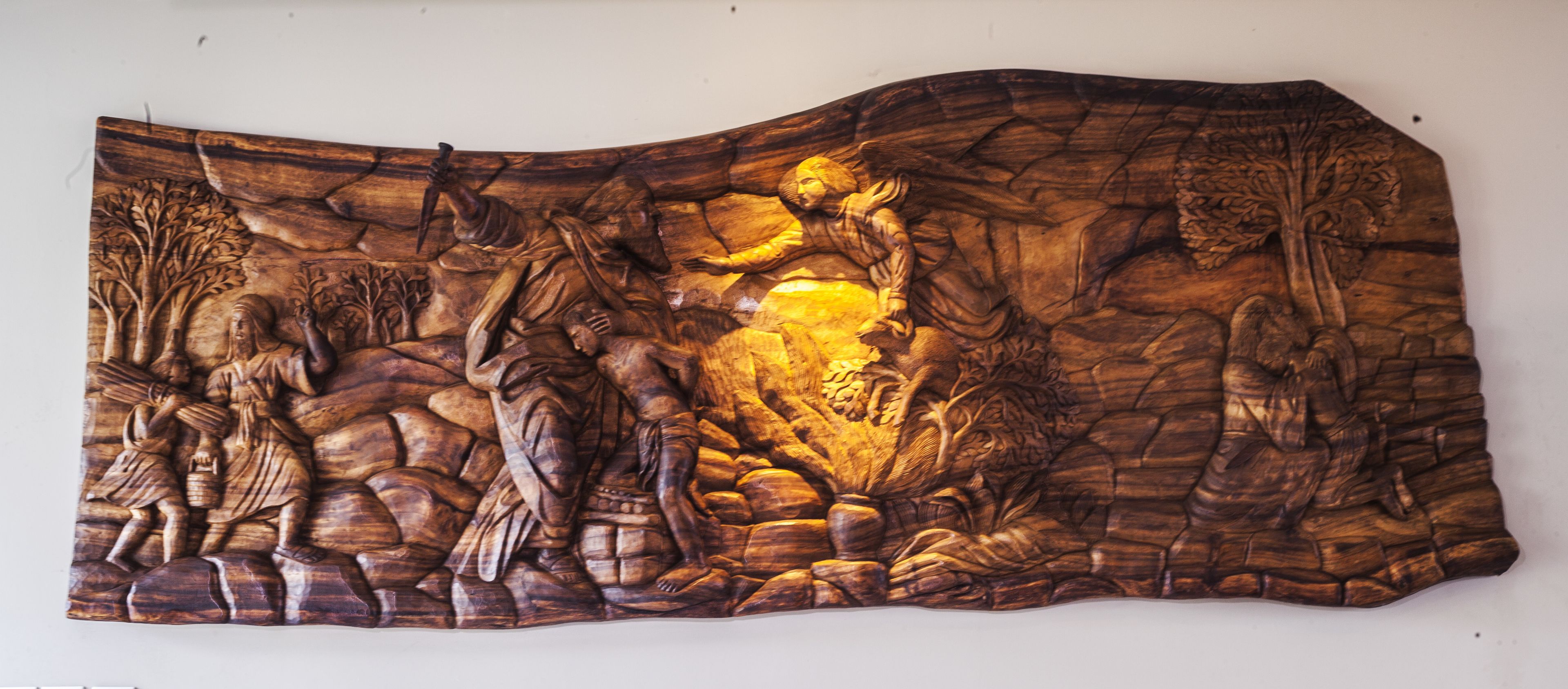 A detailed wooden carving with figures and trees.
