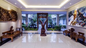 A spacious lobby with a polished floor, wooden benches, a central sculpture, and a large abstract painting. - Bale Ocasa (Tangerang)