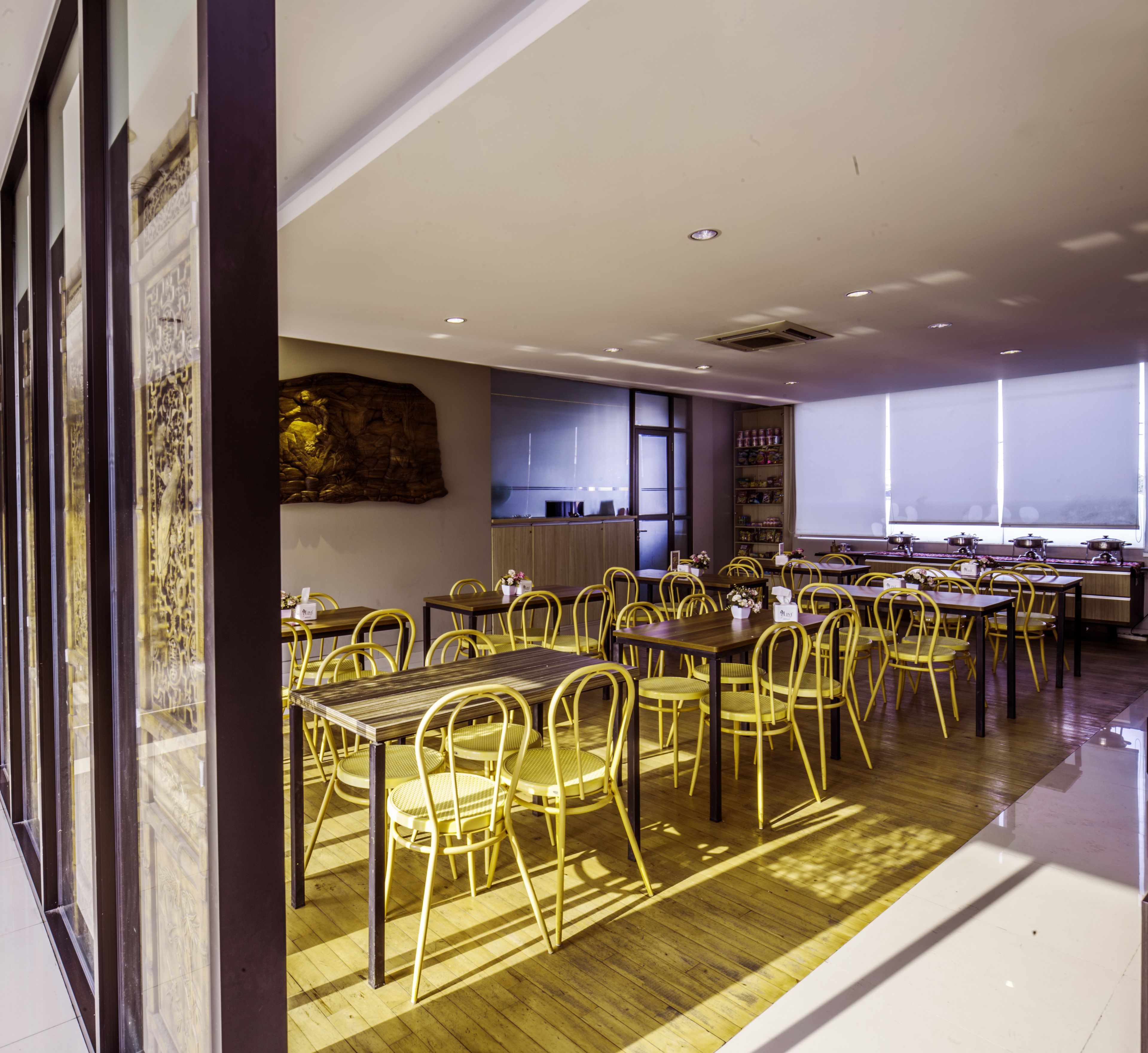 Un comedor amplio con varias mesas y sillas, un ventanal que proporciona luz natural y un elemento decorativo en la pared.