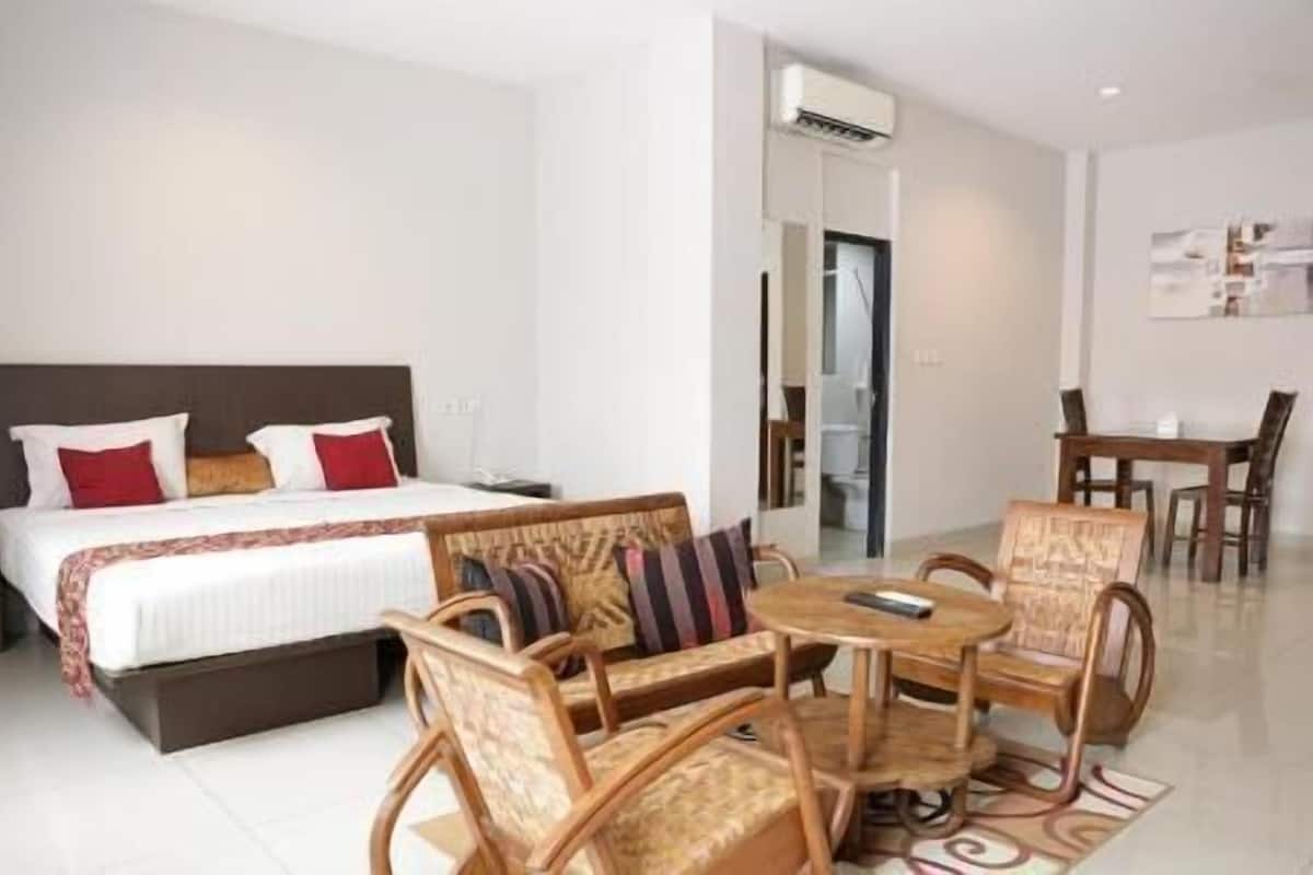 A hotel room with a bed, a dining table with chairs, and an air conditioning unit.