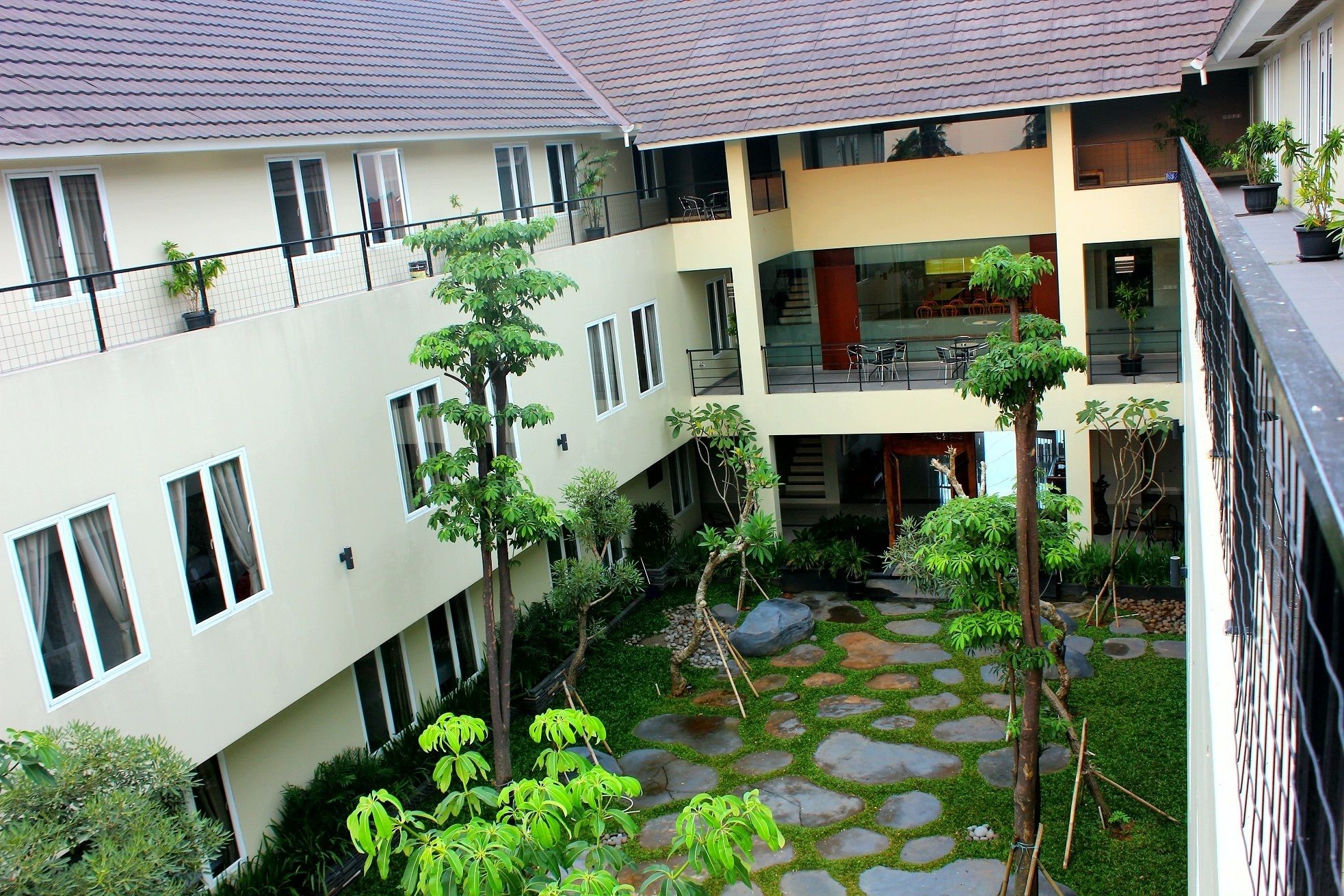 A multi-story building with a courtyard featuring stone pathways and greenery.