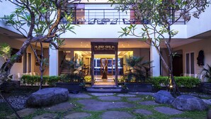 A modern building with a covered entrance, outdoor seating, and a well-maintained garden with stone pathways and large rocks. - Bale Ocasa (Tangerang)