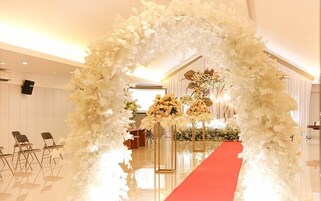 An indoor venue with a red carpet leading to a floral archway.