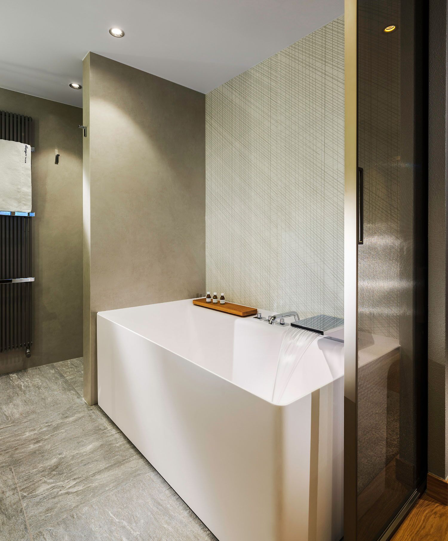 A modern bathroom with a large bathtub, a towel rack, and a glass shower enclosure.