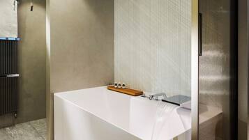 A modern bathroom with a large bathtub, a towel rack, and a glass shower enclosure.