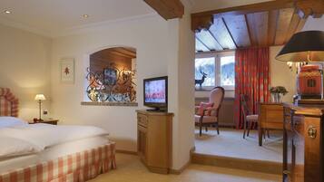 A hotel room with a bed, a television, a desk with a lamp, and a view of the outdoors.