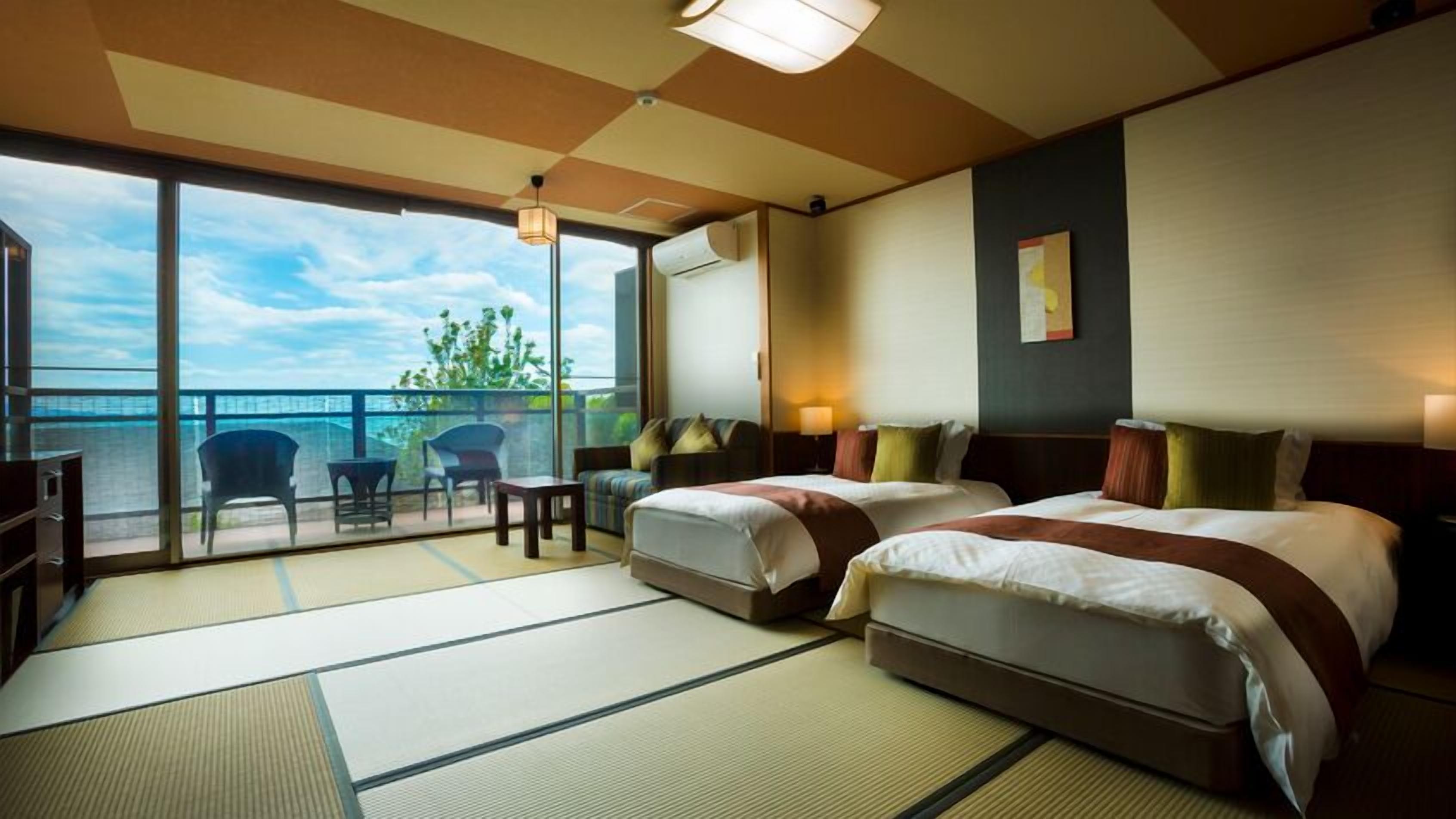 A hotel room with two beds, a balcony with a view, tatami mats, and a ceiling fan.