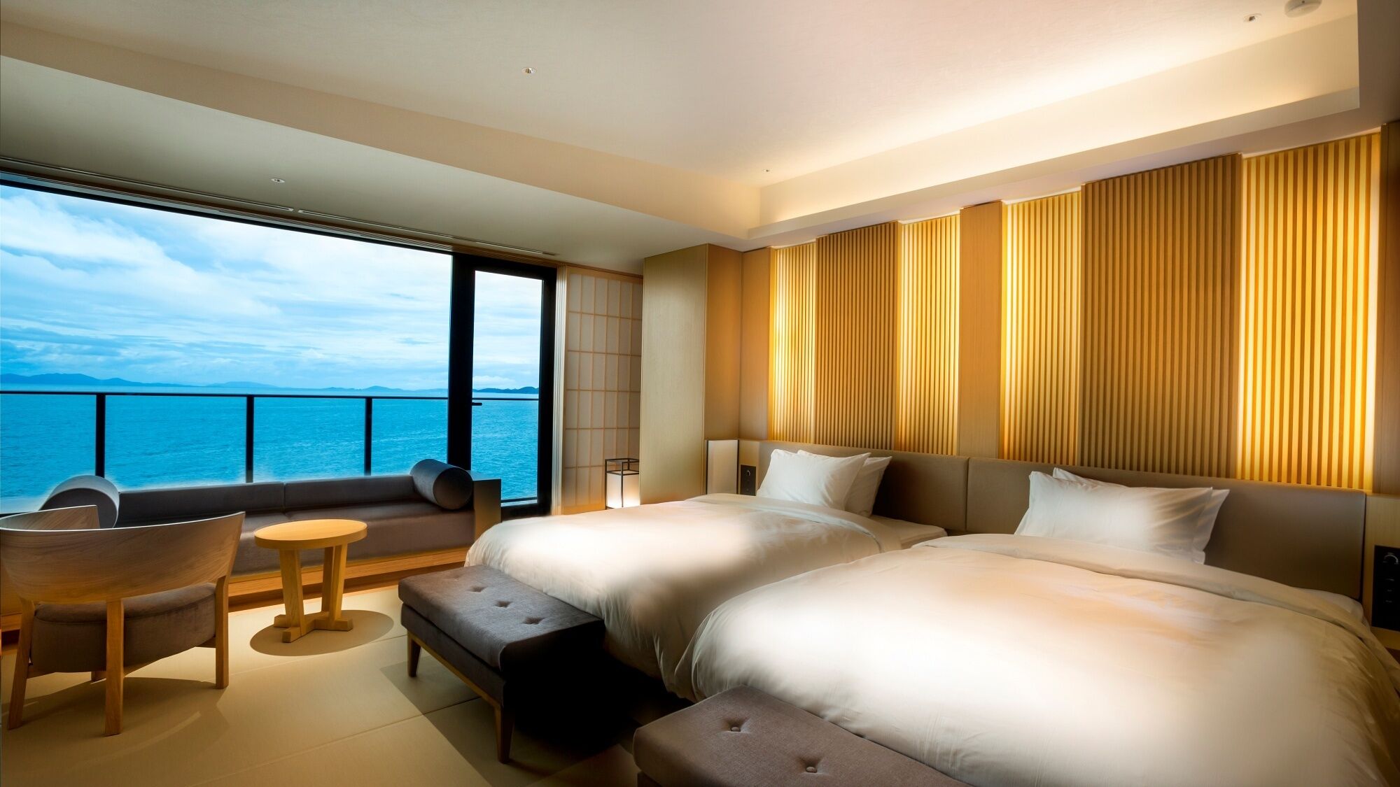 Habitación de hotel con una cama grande, un sofá, una mesita y vistas al mar.