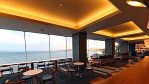 Zona de bar moderna con mobiliario de madera y amplias ventanas con vista al mar.