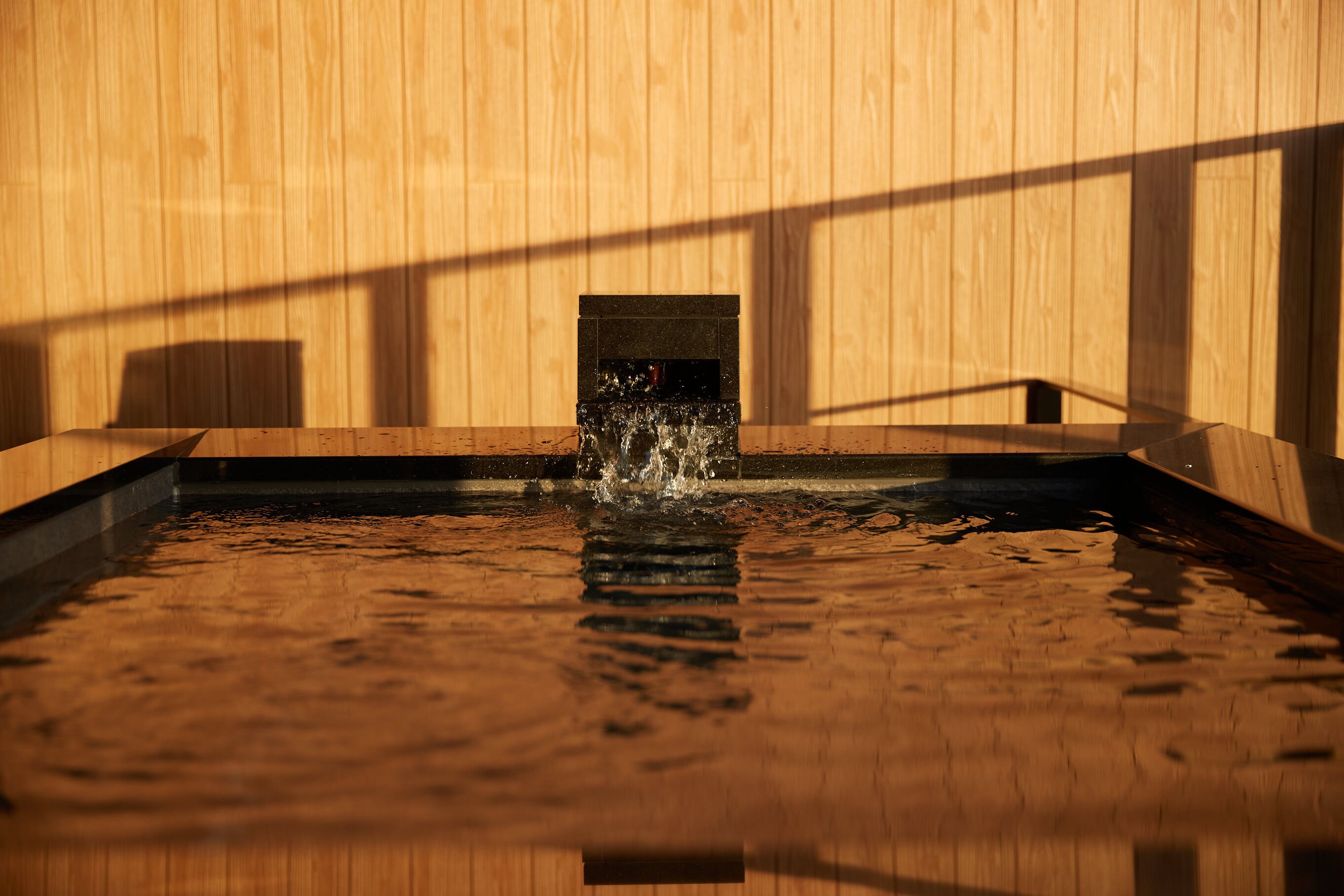Interior de madera con una fuente de agua y un ventanal pequeño.