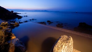 Una playa tranquila con cielo despejado, mar en calma y costa rocosa.