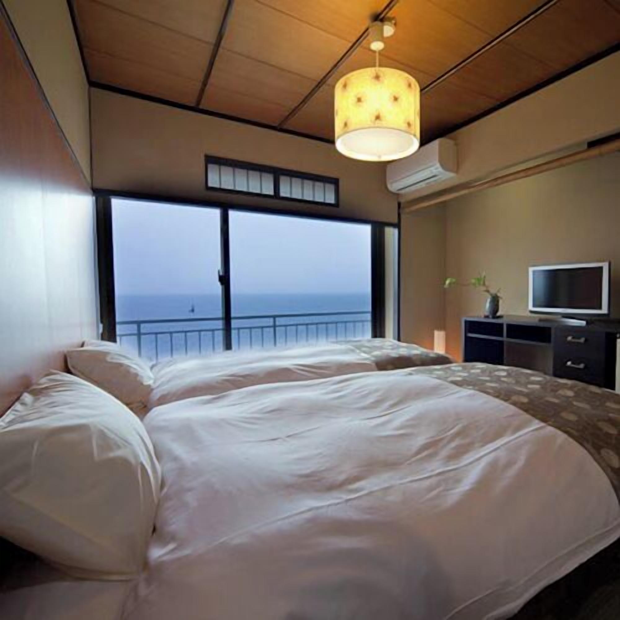 Un dormitorio con una cama grande, televisión y vista al mar.