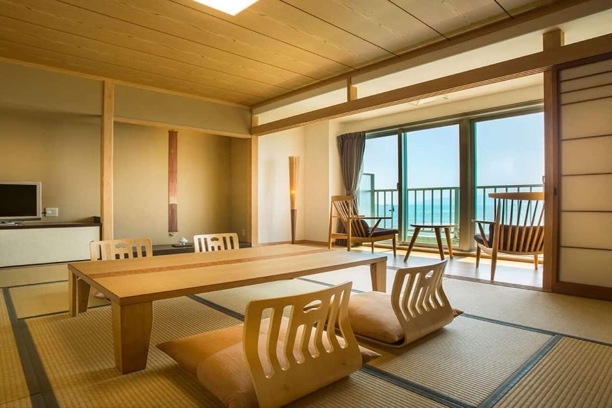 A traditional Japanese-style room with tatami flooring, a wooden dining table, and a television.