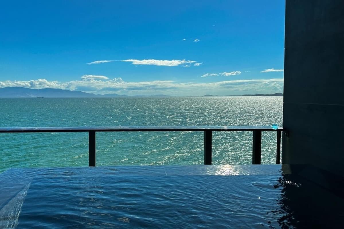A balcony with a view of the ocean and distant mountains.