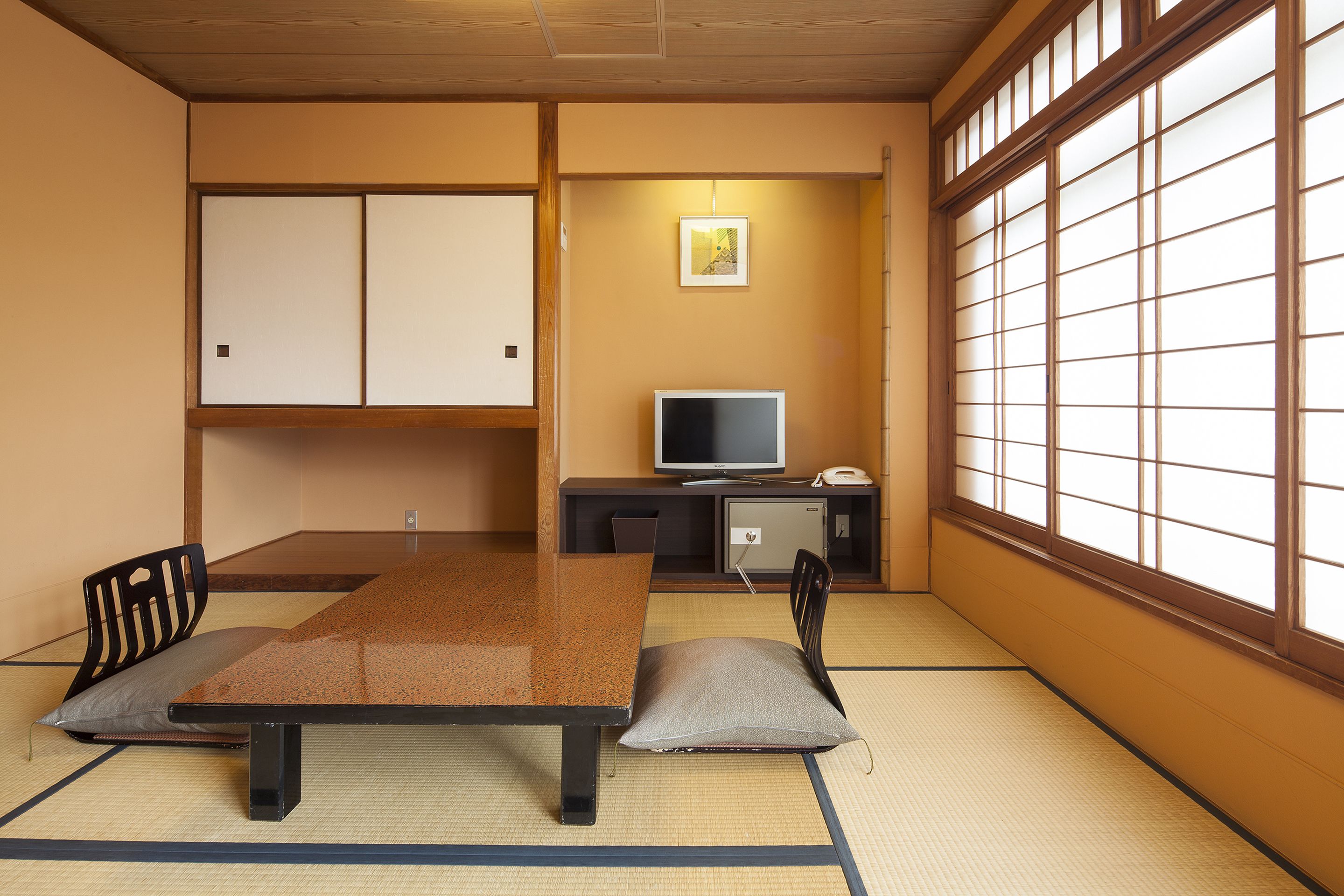 Una habitación japonesa tradicional con suelo de tatami, una mesa baja y un televisor.