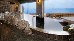 Zona de hidromasaje con pared de piedra, terraza de madera y vista al océano.