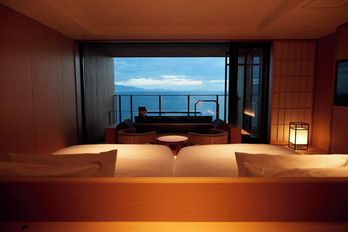 A hotel room with a balcony, a sofa, a small table, and a view of the sea.