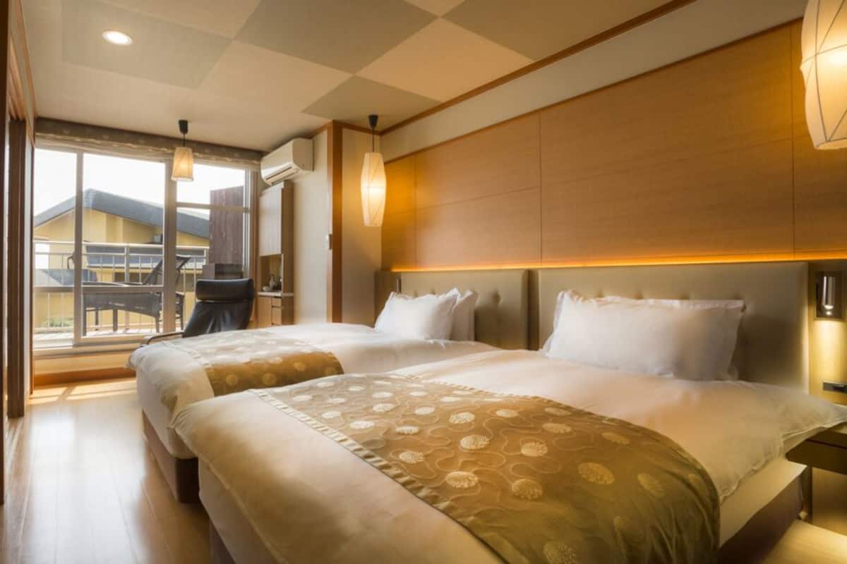 A hotel room with a large bed, a desk, and a view of a building outside.