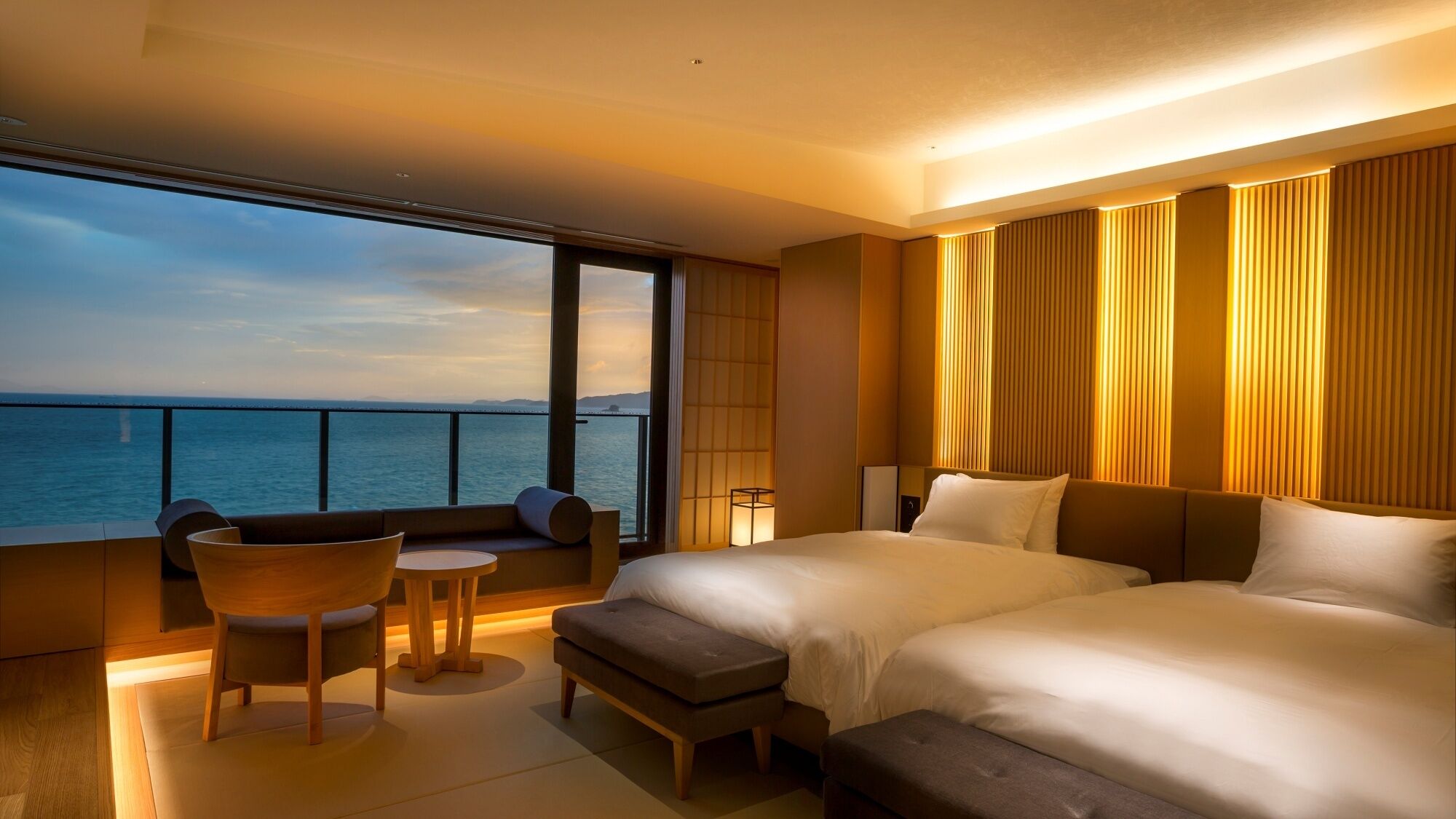 Habitación de hotel con una cama grande, un espacio de descanso pequeño y vista al mar.