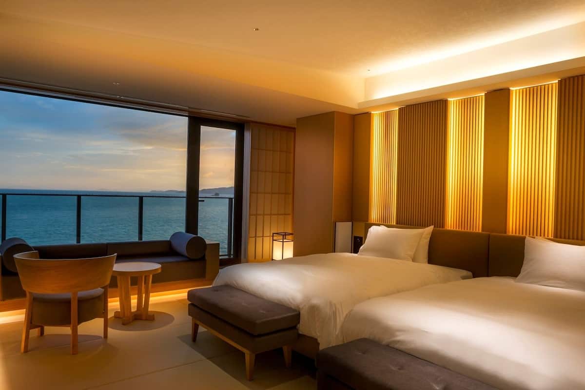 Habitación de hotel con una cama grande, un espacio de descanso pequeño y vista al mar.