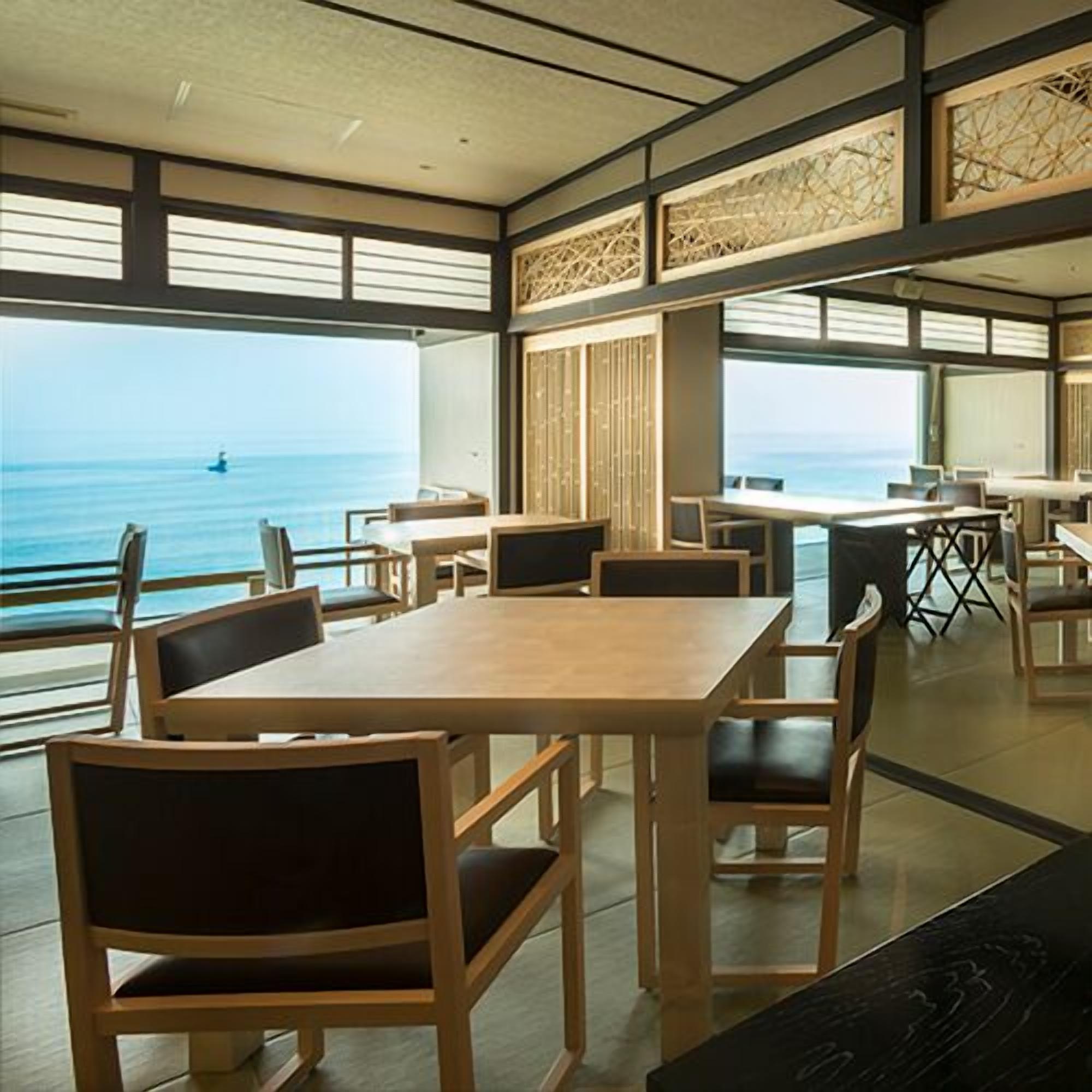 Una habitación con un ventanal grande con vista al mar, muebles de madera y una vista del océano.