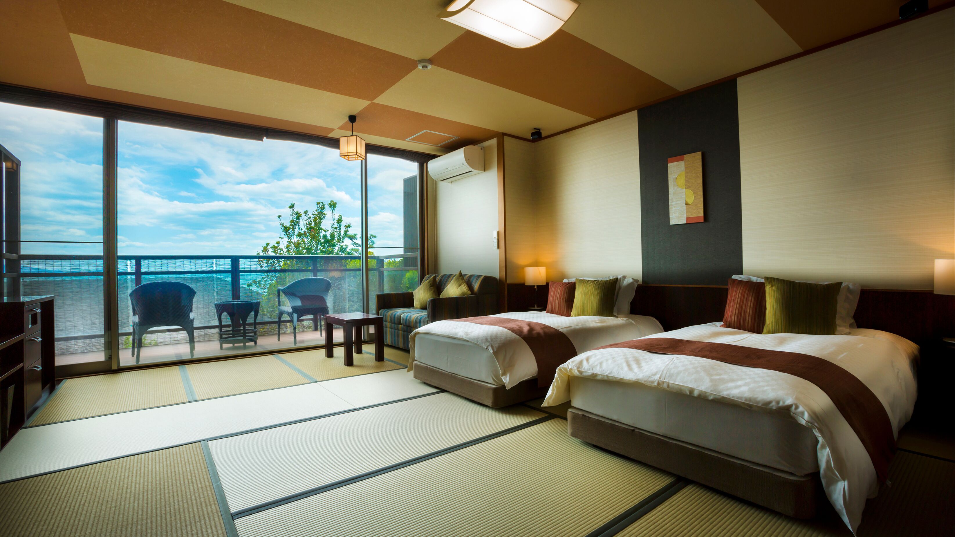 Una habitación de hotel con dos camas, un balcón con vistas y un suelo tradicional de tatami japonés.