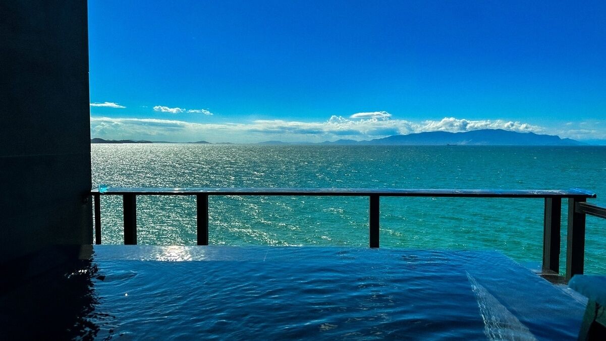 Un balcón con vista al océano y montañas a lo lejos.