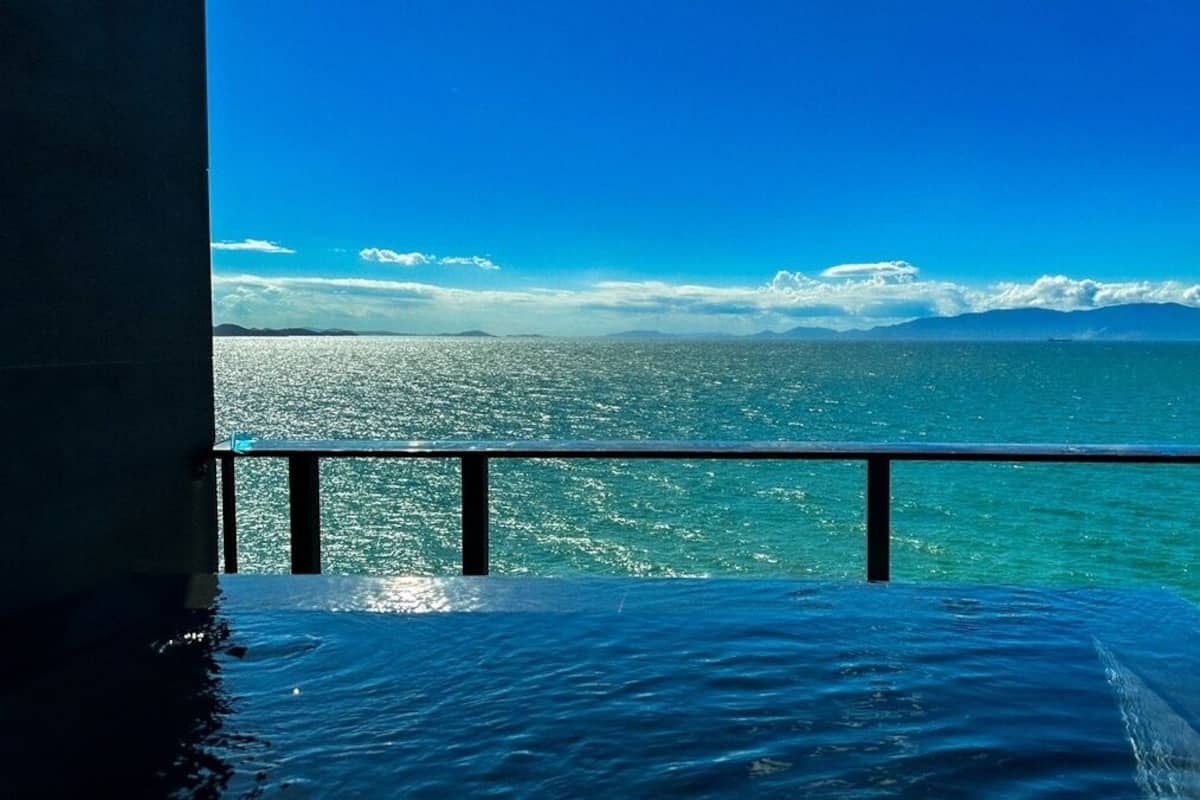 A balcony with a view of the ocean and distant mountains.