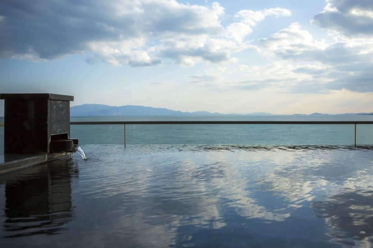 An infinity pool with a clear view of the sea and mountains.