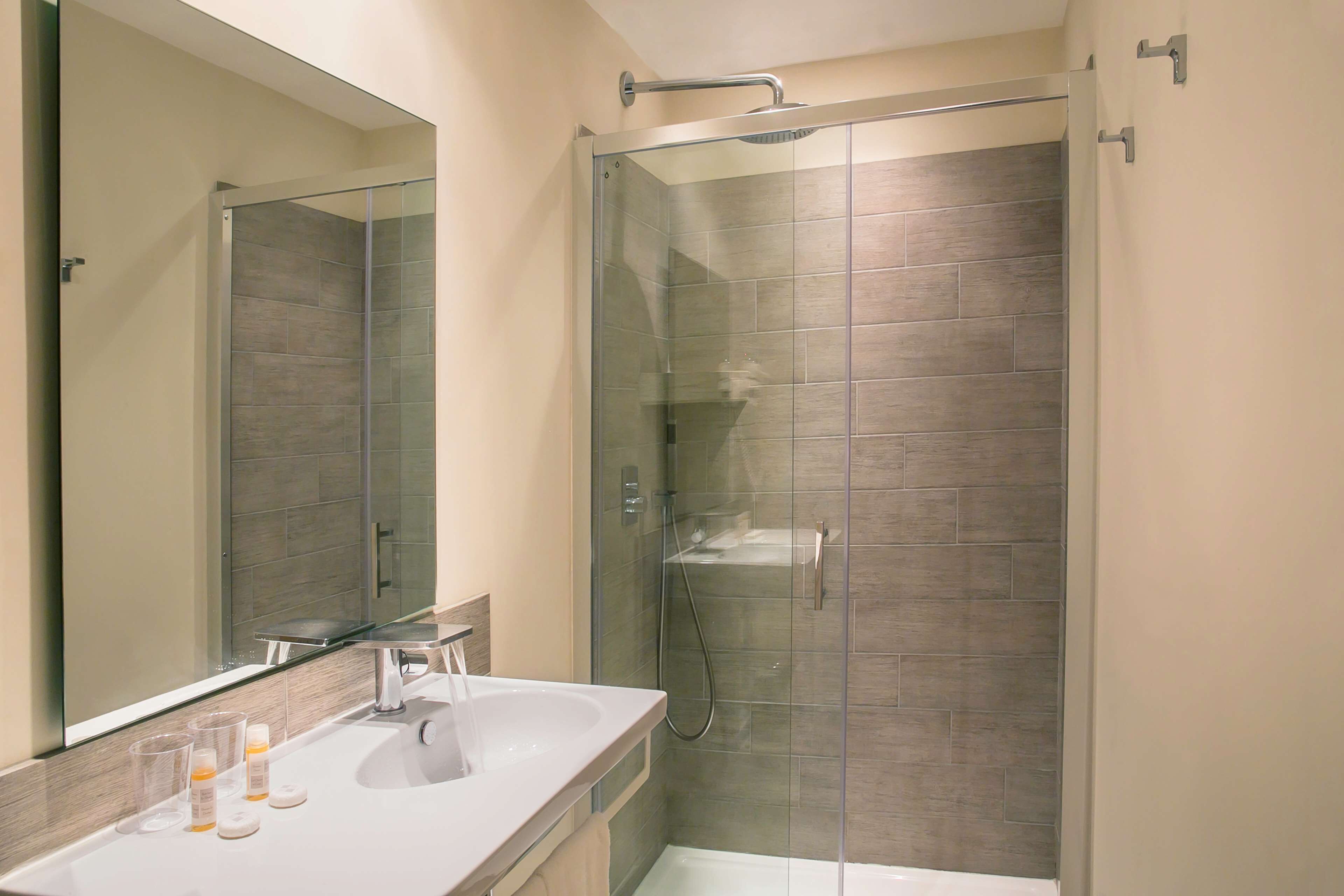 Une salle de bain moderne avec une douche à parois de verre, un lavabo blanc et un grand miroir.