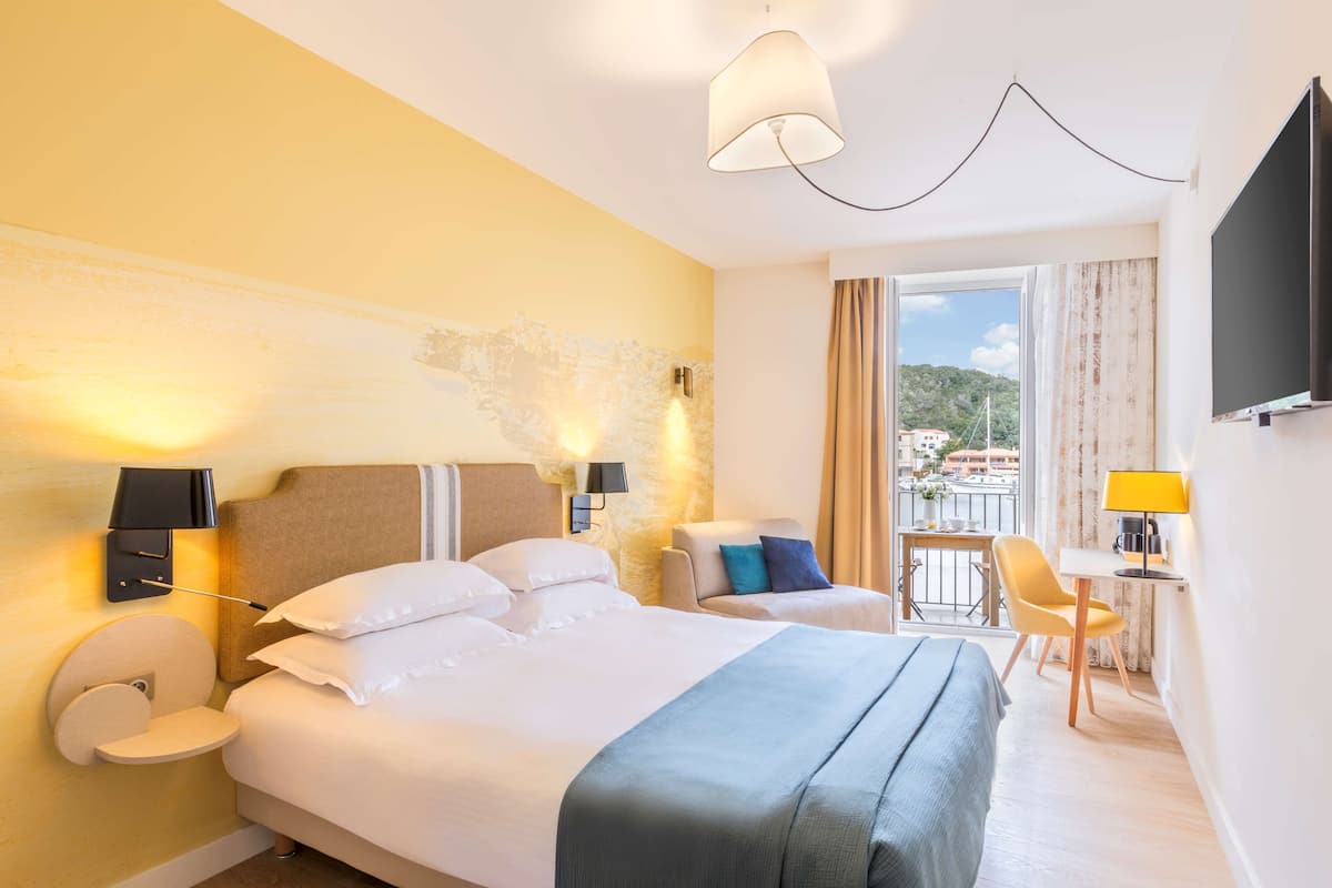 Une chambre d’hôtel avec un grand lit, un bureau, une chaise et un balcon avec vue.